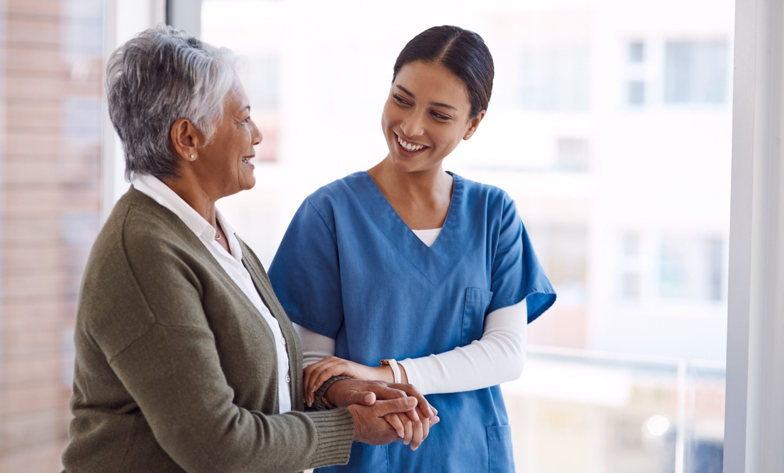 caregiver supporting senior woman indoors scaled